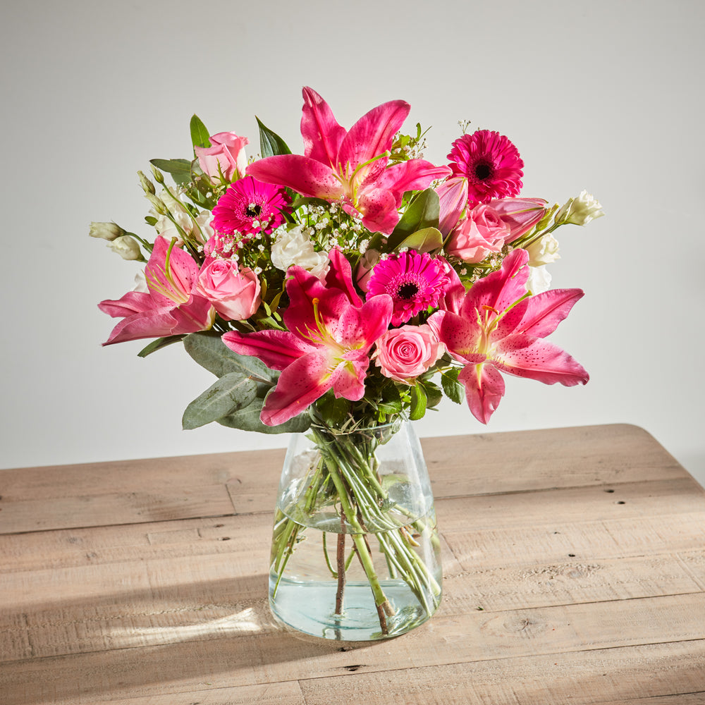 Bright pink bouquet with stargazer lilies, gerbera daisies, and pink roses.